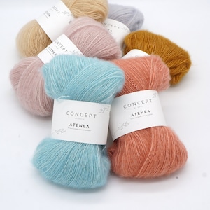 May include: Assortment of colourful yarn skeins in shades of light blue, pink, peach, beige, and mustard yellow. Each skein has a white label with the text "CONCEPT by KATIA ATENEA" printed on it.