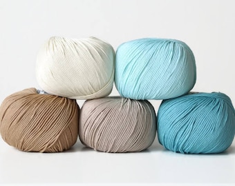 May include: Five balls of yarn in various shades of blue, brown, and white. The yarn is arranged in a pyramid shape.