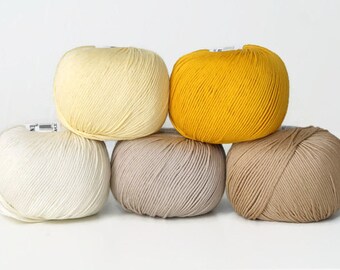 May include: Five balls of yarn in different colors: white, pale yellow, yellow, beige, and brown.