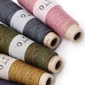 Puede incluir: Primer plano de varios carretes de hilo en varios colores, incluyendo rosa, gris, verde, amarillo y morado. Cada carrete tiene una etiqueta blanca con el texto "ITC" y "ho-yo-yo.com". El hilo parece ser una mezcla de colores.