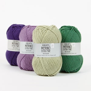 May include: Four skeins of Drops Merino Extra Fine yarn in purple, lavender, light green, and dark green. The yarn is 100% wool and is superwash treated.
