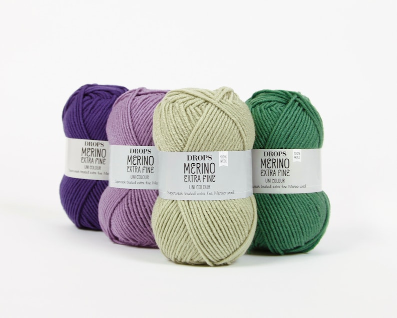 May include: Four skeins of Drops Merino Extra Fine yarn in purple, lavender, light green, and dark green. The yarn is 100% wool and is superwash treated.