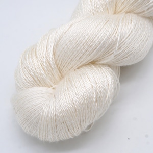 May include: A skein of off-white yarn, tightly wound and textured. The yarn appears soft and has a slight sheen, suggesting a natural fiber. Ideal for knitting or crochet projects.