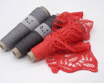 May include: Three spools of yarn in gray and dark gray, with a vibrant red knitted fabric. The yarn spools have labels with the text "ito". The knitted fabric has an open, lacy design.