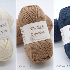 May include: Three balls of yarn in different colours: white, brown, and blue. Each ball has a label that reads "Ros&aacute;rios 4 Capuccino Ecofriendly Collection".