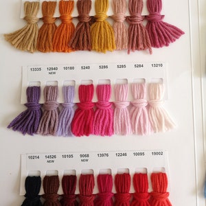 Puede incluir: Una carta de colores con muestras de hilo en varios tonos de marr&oacute;n, naranja, rojo, rosa, morado y negro. Las muestras de hilo est&aacute;n dispuestas en filas y columnas, con cada muestra etiquetada con un n&uacute;mero.