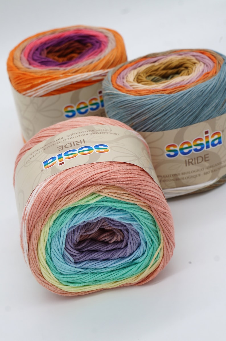 Puede incluir: Tres ovillos de hilo de algod&oacute;n Sesia Iride en colores arco&iacute;ris. El hilo es 100% algod&oacute;n org&aacute;nico y est&aacute; hecho en Italia. Los ovillos est&aacute;n etiquetados con el nombre de la marca y el nombre del hilo.