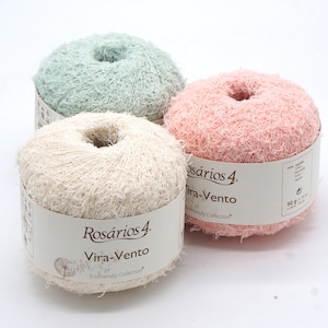 May include: Three balls of yarn in different colours: light green, beige, and pink. Each ball has a label that says "Rosários 4 Vira-Vento Ecofriendly Collection" and "50 g (1.75 oz)".