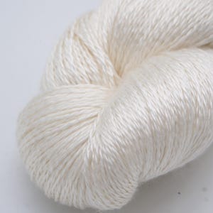 May include: A close-up of a skein of off-white yarn. The yarn is tightly wound, showing a textured surface. The fibers appear soft and have a slight sheen, suggesting a natural fiber like silk or linen. Ideal for knitting or crochet projects.