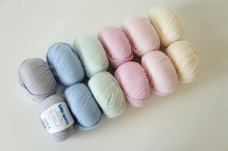 Puede incluir: Diez ovillos de lana en varios colores pastel, incluyendo azul claro, verde p&aacute;lido, rosa y crema. La lana est&aacute; etiquetada como "Lana Gatto Super Soft".