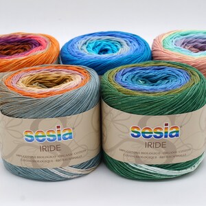 Puede incluir: Cinco ovillos de hilo Sesia Iride en diferentes combinaciones de colores. El hilo es 100% algod&oacute;n org&aacute;nico y est&aacute; disponible en una variedad de colores. El hilo est&aacute; empaquetado en un tubo de cart&oacute;n con una etiqueta que dice "Sesia Iride" y "100% cotone biologico - organic cotton - coton biologique - bio baumwolle".