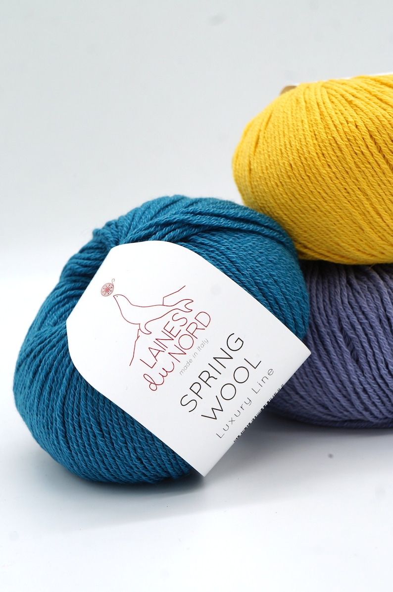 May include: Three balls of yarn in different colors: teal, yellow, and purple. The teal ball has a white label that says "Laines du Nord made in Italy Spring Wool Luxury Line".