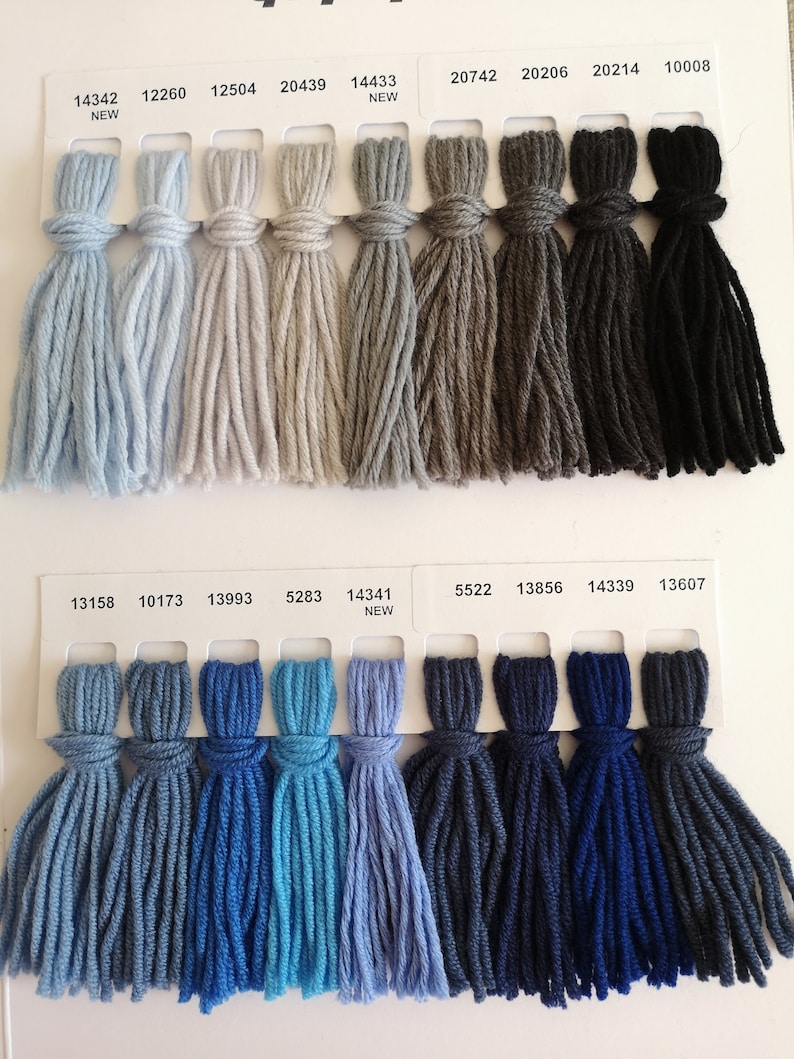 Puede incluir: Una carta de colores con muestras de hilo en varios tonos de gris, azul y negro. La carta incluye los n&uacute;meros de hilo y la palabra "NEW" junto a algunas de las muestras.