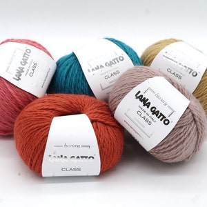 May include: Five balls of yarn in different colours: pink, orange, teal, beige, and light pink. Each ball has a white label with the text "luxury LANA GATTO MADE IN ITALY CLASS" printed on it.