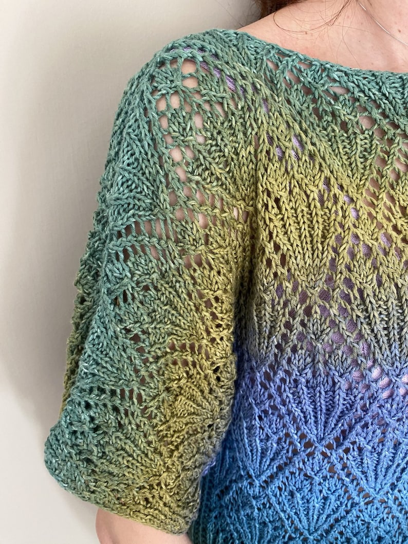 Puede incluir: Un top de crochet de color verde, amarillo y azul con un patr&oacute;n de encaje.