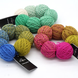 May include: A collection of colourful yarn balls in shades of green, blue, yellow, pink, and white. The yarn balls are arranged in a circle and have a striped pattern.