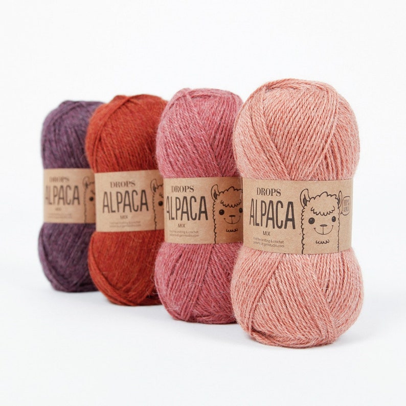 May include: Four skeins of yarn in different shades of pink, red, and purple. Each skein has a label that reads "DROPS ALPACA MIX" with a cartoon alpaca on it.