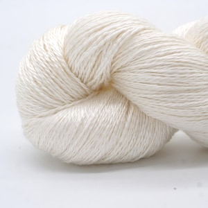 May include: A close-up of a skein of off-white yarn. The yarn is tightly wound, with visible strands and a soft, textured appearance. The yarn is likely used for knitting or crocheting projects.