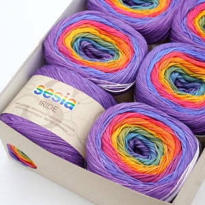 Puede incluir: Una caja de seis ovillos de hilo de colores arco&iacute;ris. El hilo est&aacute; hecho de algod&oacute;n org&aacute;nico 100%. La etiqueta dice "Sesia Iride 100% Cotone Biologico Organic Cotton Coton Biologique Bio Baumwolle".
