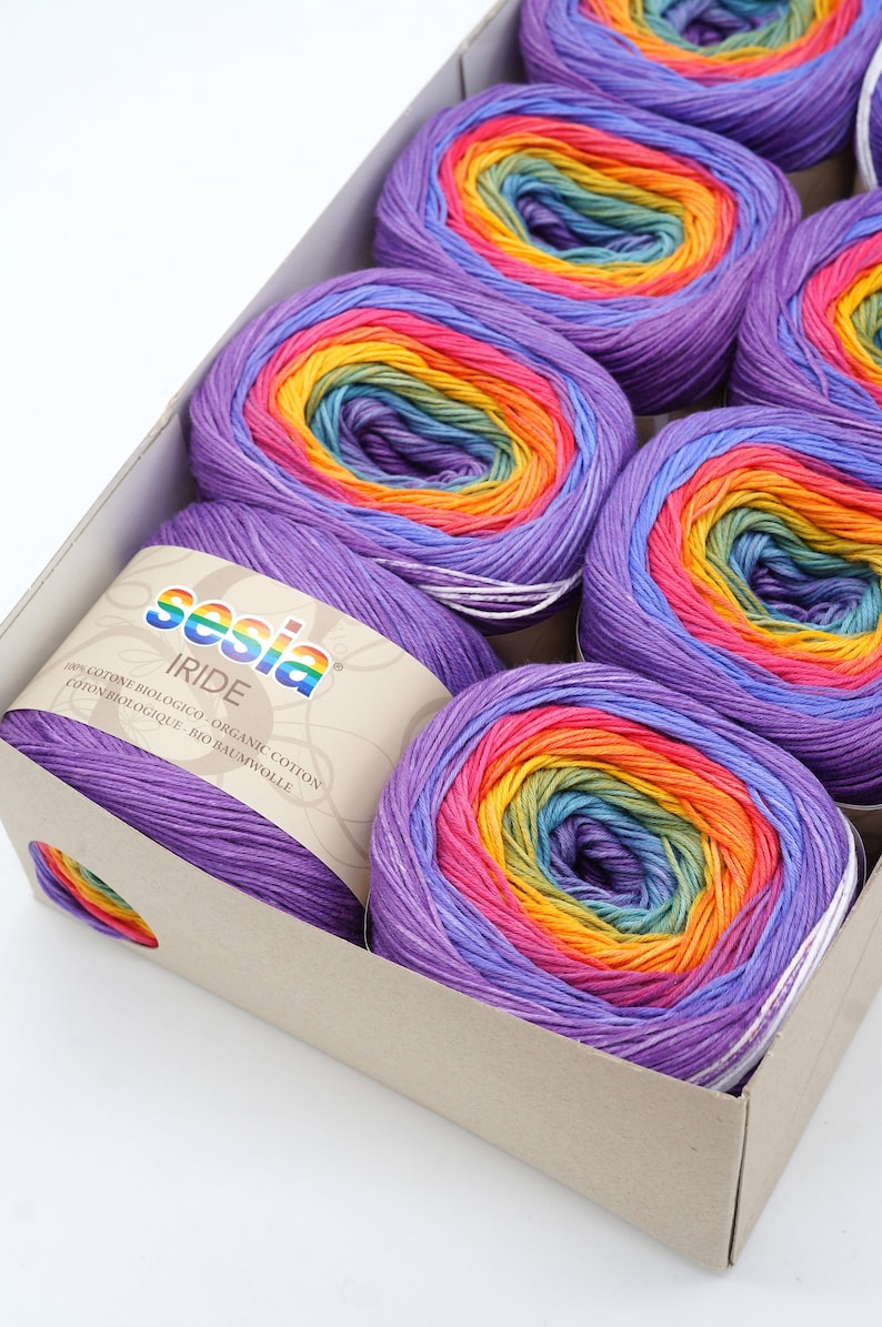 Puede incluir: Una caja de seis ovillos de hilo de colores arco&iacute;ris. El hilo est&aacute; hecho de algod&oacute;n org&aacute;nico 100%. La etiqueta dice "Sesia Iride 100% Cotone Biologico Organic Cotton Coton Biologique Bio Baumwolle".