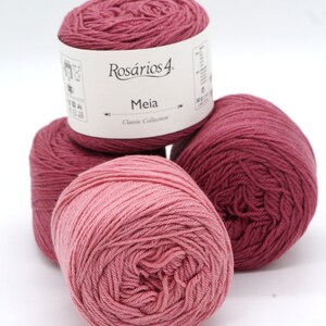 May include: Three balls of pink yarn, one with a label that reads "Ros&aacute;rios 4. Meia Classic Collection"