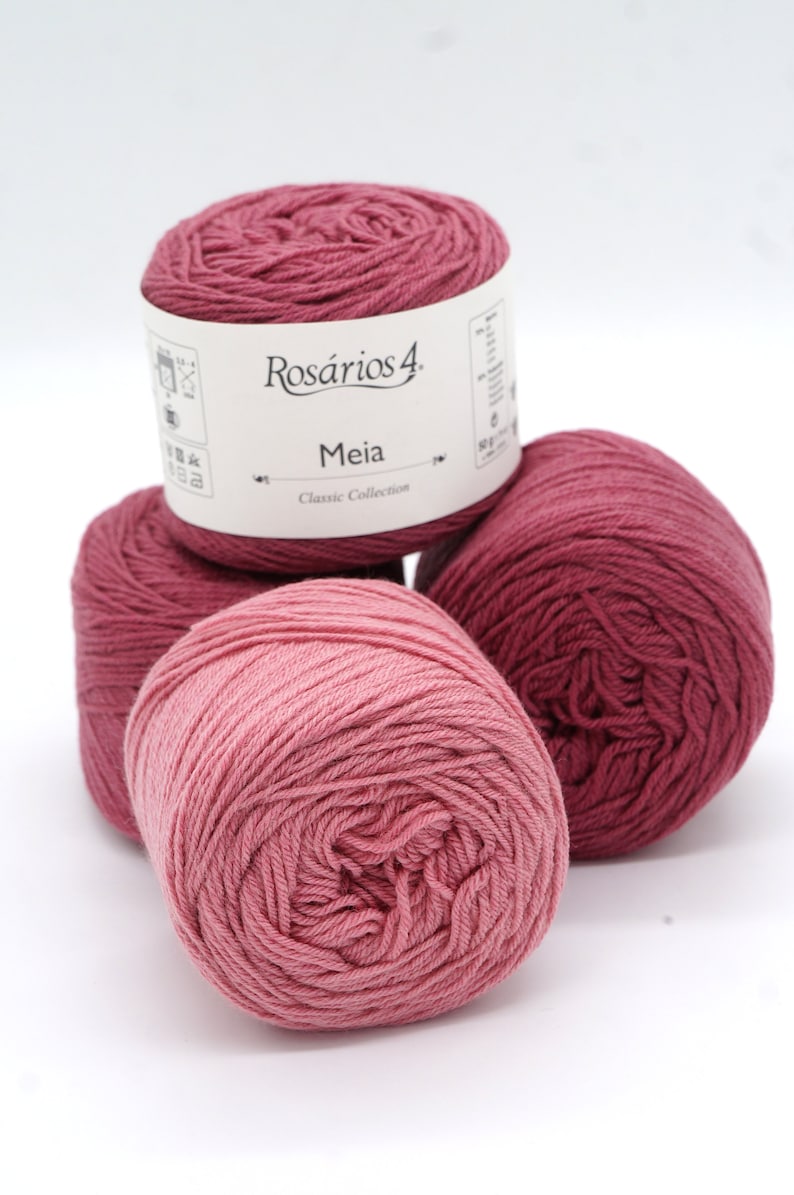 May include: Three balls of pink yarn, one with a label that reads "Ros&aacute;rios 4. Meia Classic Collection"