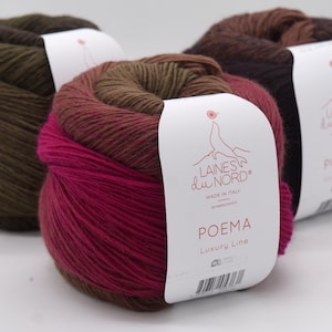 May include: Three skeins of Laines du Nord Poema yarn featuring a gradient of colors including olive green, deep magenta, and dark brown. Each skein has a white paper label with the brand logo, the text Poema Luxury Line, and a barcode.