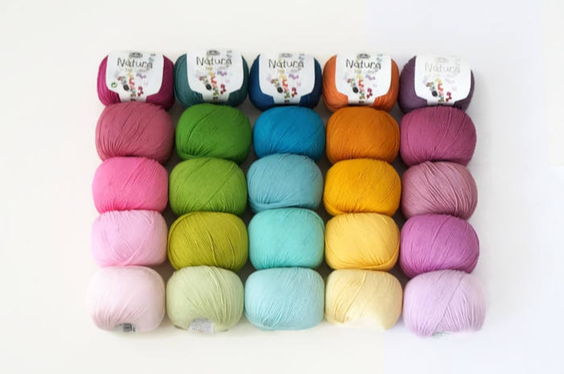 May include: A collection of 20 skeins of yarn in various shades of pink, green, blue, yellow, and purple. The yarn is arranged in rows of five, with each row featuring a different color. The yarn is labeled "Natura" on the skeins.