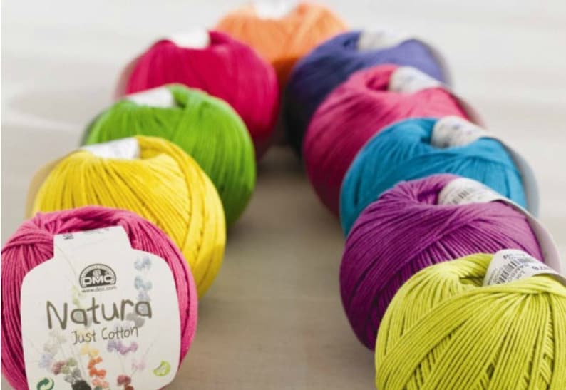 May include: A row of colorful yarn balls in shades of pink, yellow, green, blue, and purple. The yarn is labeled "Natura Just Cotton" and is made by DMC.