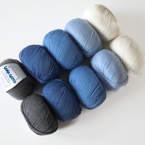 Puede incluir: Una colecci&oacute;n de ocho ovillos de lana en tonos de azul, gris y blanco. Los ovillos de lana est&aacute;n dispuestos en degradado de gris oscuro a blanco. La lana est&aacute; etiquetada como "Lana Gatto" y "Super Soft".