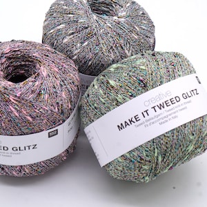 Könnte beinhalten: Drei Knäuel Garn in verschiedenen Farben: rosa, grün und grau. Jedes Knäuel hat ein Etikett mit der Aufschrift "Make It Tweed Glitz" und enthält Informationen über das Garn, wie z. B. das Material und den Herstellungsort.