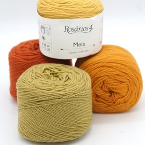 May include: Three balls of yarn in shades of orange, yellow, and green. The yarn is labeled "Ros&aacute;rios 4 Meia Classic Collection".