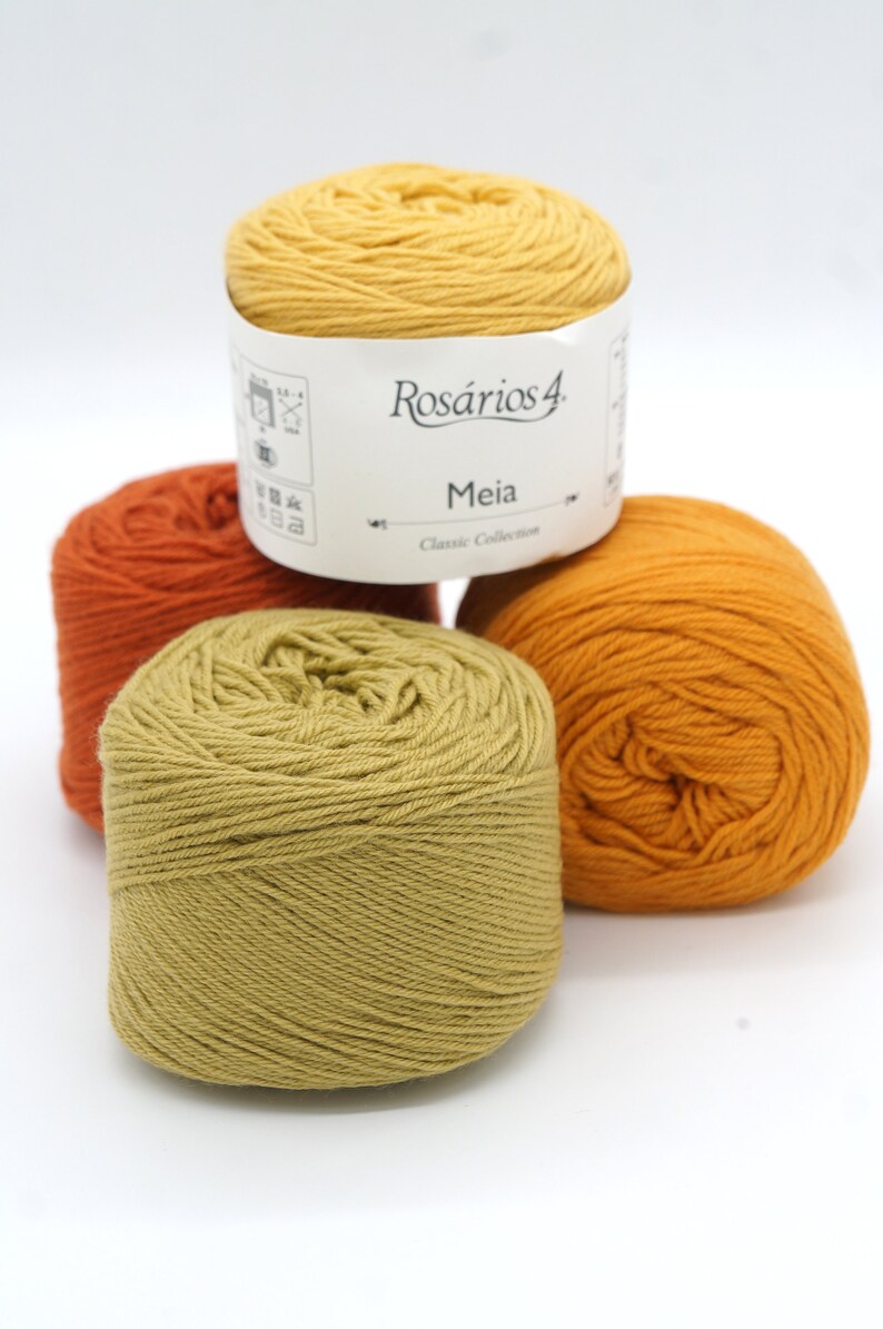 May include: Three balls of yarn in shades of orange, yellow, and green. The yarn is labeled "Ros&aacute;rios 4 Meia Classic Collection".