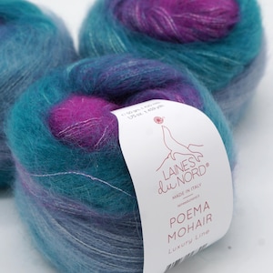 Puede incluir: Tres ovillos de hilo mohair colorido en tonos turquesa, morado y azul. El hilo está etiquetado como "POEMA MOHAIR Luxury Line" y "Colour 7". Cada ovillo pesa aproximadamente 50 g.