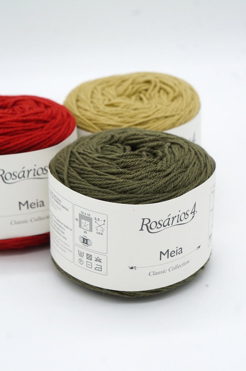 May include: Three balls of yarn in red, yellow, and green. The yarn is labeled "Ros&aacute;rios 4 Meia Classic Collection" and includes care instructions.