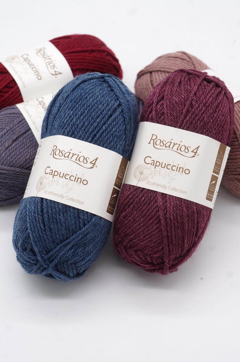 May include: Four balls of yarn in different colours: red, pink, blue, and burgundy. Each ball has a label that says "Ros&aacute;rios 4. Capuccino Ecofriendly Collection".