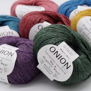 May include: Assortment of yarn skeins in various colours, including teal, purple, green, red, and yellow. Each skein has a white label with the text "ONION Knit No. 4 Organic Wool + Nettles" and the brand name "ONION".