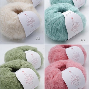 Pu&ograve; includere: Quattro gomitoli di filato soffice in crema, verde acqua, verde salvia e rosa. Ogni gomitolo ha un'etichetta con la scritta "LAINES du NORD PLUME MADE IN ITALY". Il filato &egrave; morbido e sembra essere fatto di mohair o fibra simile.