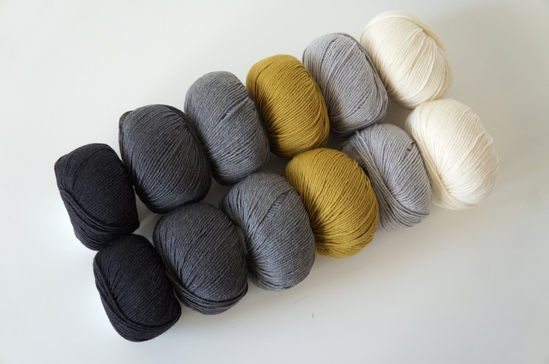 Puede incluir: Una colecci&oacute;n de ovillos de lana en negro, gris, amarillo y blanco. La lana est&aacute; dispuesta en un degradado de oscuro a claro.