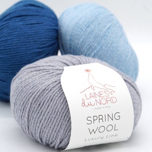 May include: Three skeins of yarn, one gray, one light blue, and one dark blue. The gray skein has a white label that reads "Laines du Nord made in Italy Spring Wool Luxury Line".