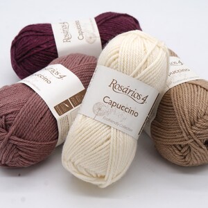 May include: Four balls of yarn in different colours: burgundy, light brown, beige, and a light pink. The yarn is labelled "Rosarios 4 Cappuccino" and "Eco-friendly Collection".