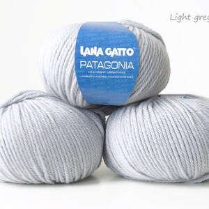 May include: Three balls of light grey yarn, labeled "Lana Gatto Patagonia" with the color code "12504".