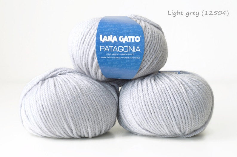 May include: Three balls of light grey yarn, labeled "Lana Gatto Patagonia" with the color code "12504".