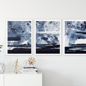 Pu&ograve; includere: Tre stampe d'arte astratta incorniciate in uno schema di colori blu e bianco. Le stampe presentano un design stratificato e testurizzato con sfumature di blu e bianco.