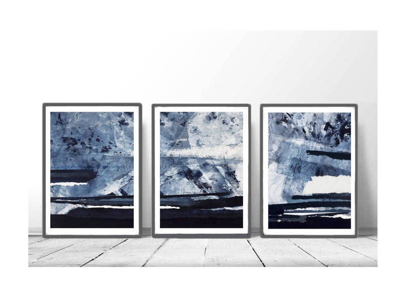Pu&ograve; includere: Tre dipinti astratti incorniciati in tonalit&agrave; di blu e bianco. I dipinti sono in cornici nere e sono appesi a una parete bianca.