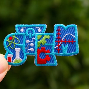 May include: A blue embroidered patch with the word "STEM" spelled out in colorful letters. Each letter is decorated with different science-related symbols, including a beaker, a gear, an atom, and a graph.