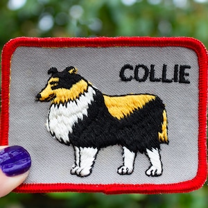 May include: A gray fabric patch with a red border, featuring an embroidered image of a black and white Collie dog with a yellow patch on its back. The word "COLLIE" is embroidered in black above the dog.