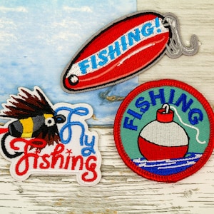 May include: Three embroidered iron-on patches with a fishing theme. The first patch is red and white with the word "FISHING!" on it. The second patch is green and white with the word "FISHING" on it and a red and white fishing bobber. The third patch is white with a fly fishing lure and the words "Fly Fishing" on it.