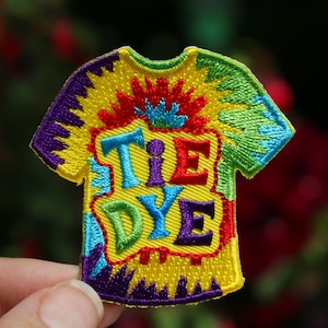 May include: A colorful embroidered iron-on patch shaped like a t-shirt with the words "TIE DYE" in a rainbow of colors.