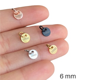 May include: A collection of small, round metal charms in various colors, including gold, silver, black, and rose gold. Each charm has a small loop and the word "LOGO" printed on it. The charms are approximately 6 mm in diameter.